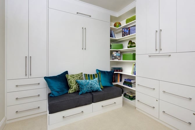 Adding under-bed storage and a bench seat helps a wall bed add utility to a smaller bedroom.